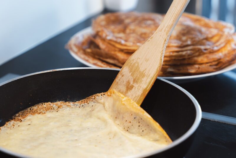 Palačinka koja se peče u tiganju uz pomoć drvene lopatice